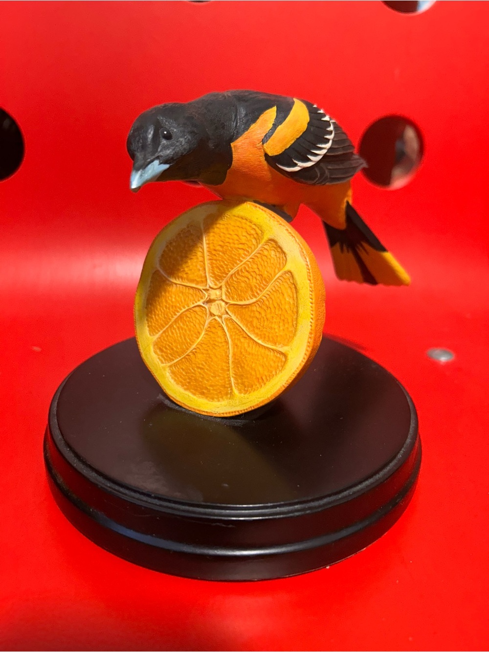 Hand-carved wooden Baltimore Oriole perched on an orange half